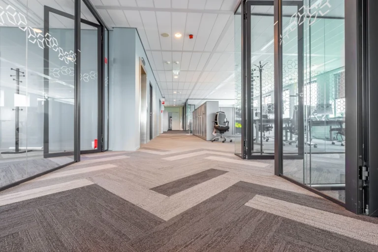 Spacious and bright modern office hallway with glass partitions and contemporary design.