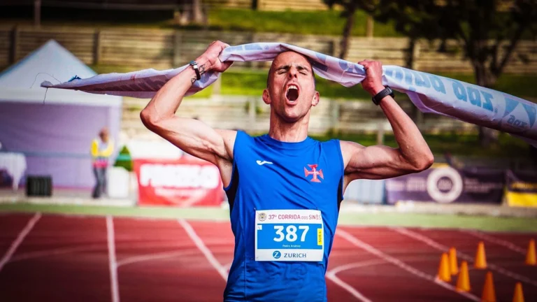 Atlet slaví vítězství na cílové čáře maratonu, triumfálně zvedající pásku nad hlavou.