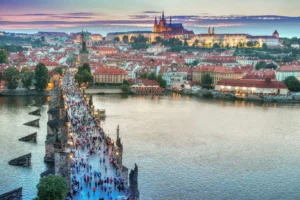 Živý pohled na Karlův most vedoucí k Pražskému hradu při západu slunce.