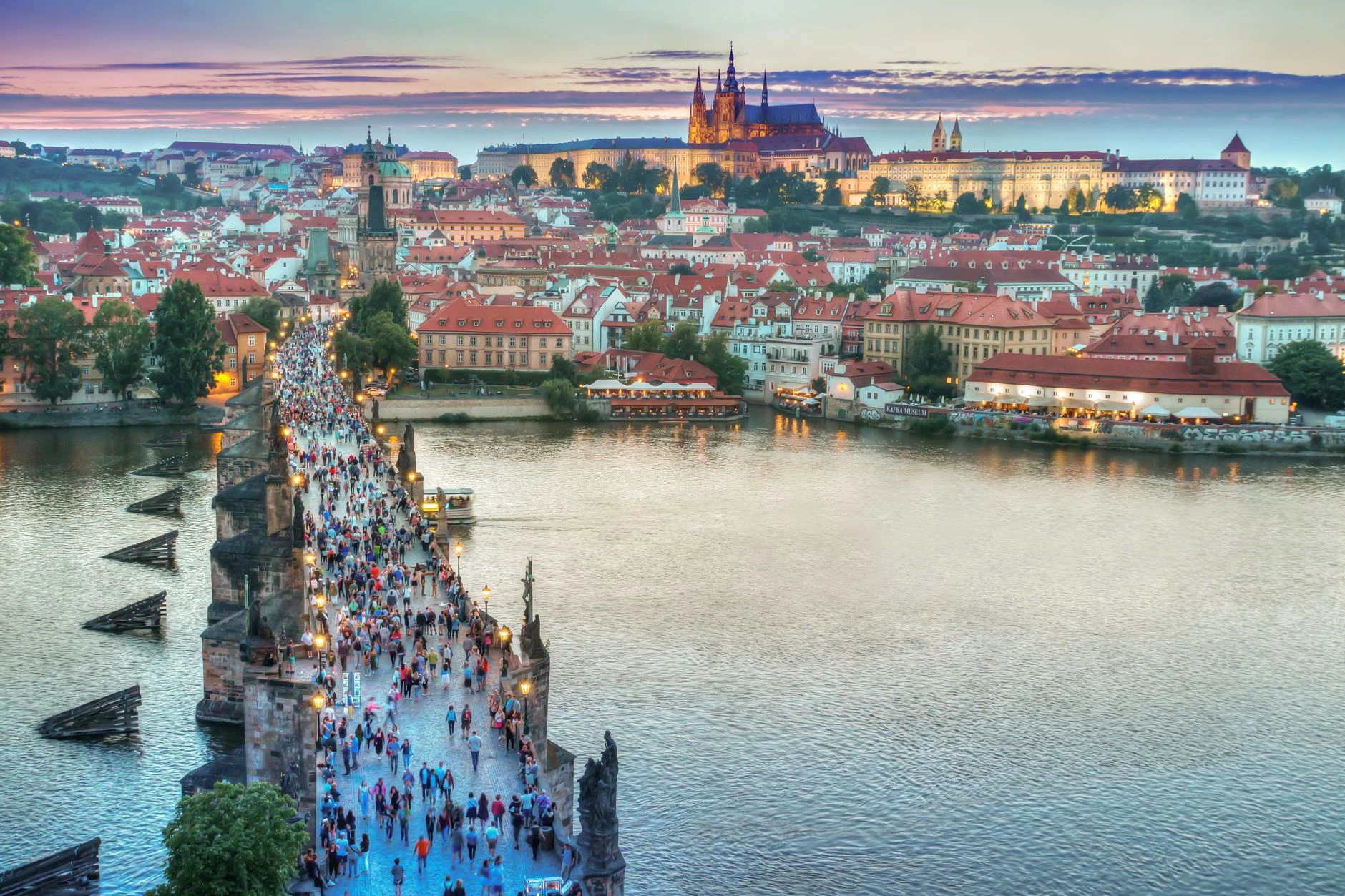 Živý pohled na Karlův most vedoucí k Pražskému hradu při západu slunce.
