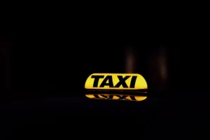 Žlutá zářící taxi značka zachycena v noci v Göteborgu, Švédsko, zdůrazňující městský život.
