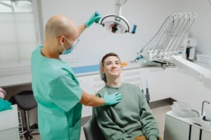 Zubař vyšetřuje pacienta pod stomatologickým světlem v moderním klinickém prostředí.