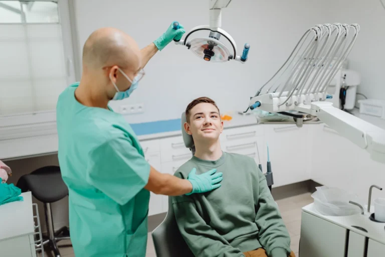 Zubař vyšetřuje pacienta pod stomatologickým světlem v moderním klinickém prostředí.