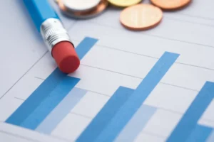 Detailní snímek sloupcových grafů s tužkou a mincemi, symbolizující finanční analýzu.