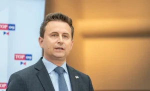 Vystoupení zástupce TOP 09 před panelem s logem strany, snímek k tiskové zprávě o kulatém stolu